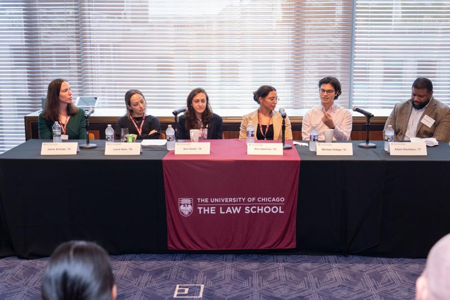 The Public Interest panel included Jamie Schulte, ’15; Lucia Goin, ’19; Sari Amiel, ’19; Alex Aparicio, '21; Michael Ortega, ’21; and moderator Professor Adam Davidson, ’17. Five panelists sit a table draped with a University of Chicago Law School tablecloth. One panelist, wearing glasses and a white button down shirt, speaks into the tabletop microphone while the other panelists look on.