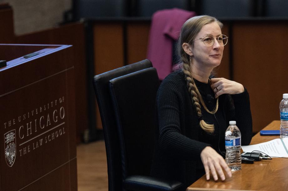 A woman sitting at a desk addressing an audience (not pictured)