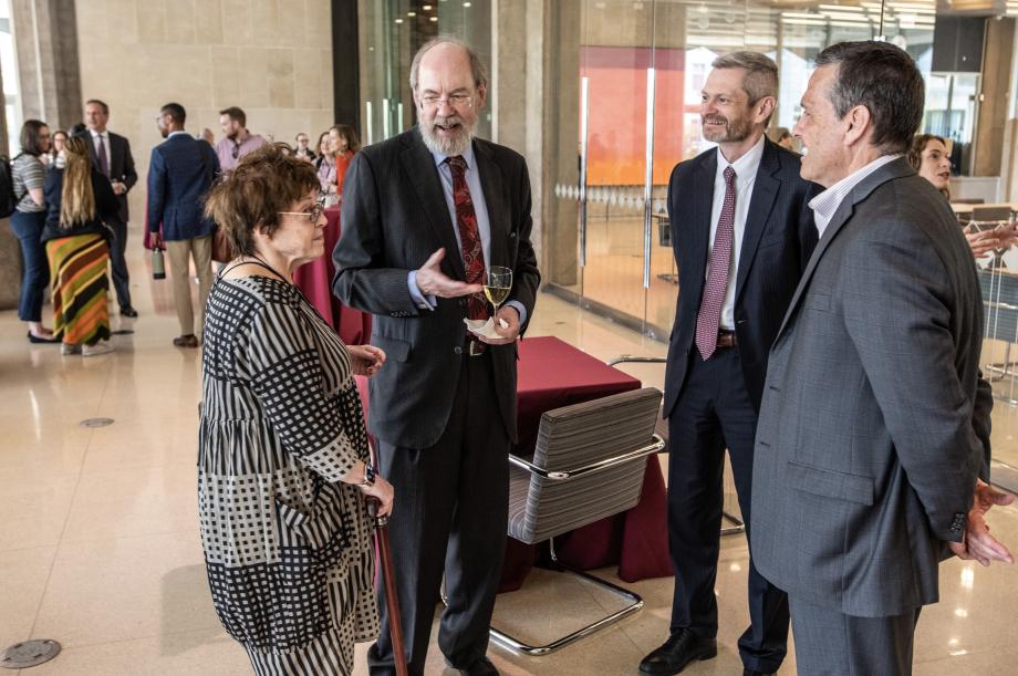 Four people are standing together having a conversation.