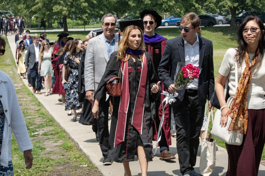 Graduates and guests make their way to the Law School's Laird Bell Quadrangle for a lunch reception... A line of people are walking down a path toward the Law School building.