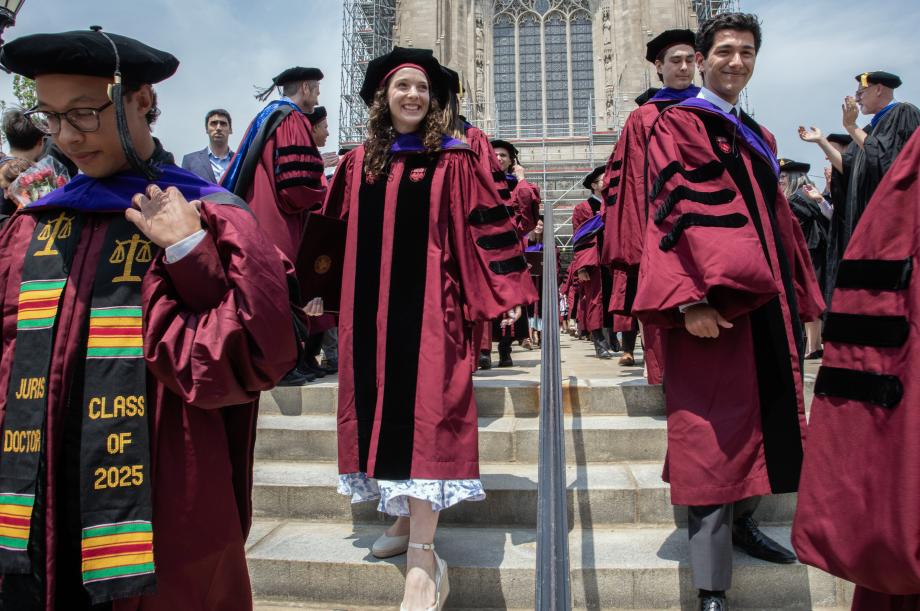 Graduates emerge from the Rockefeller Memorial Chapel to meet family and friends after the ceremony. Graduates are exiting the chapel, descending stairs while smiling.