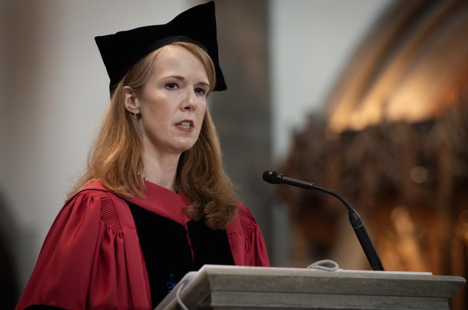 A woman in cap and gown behind a podium.