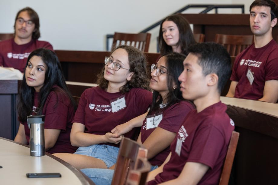 Students listening to someone speak in a classroom.
