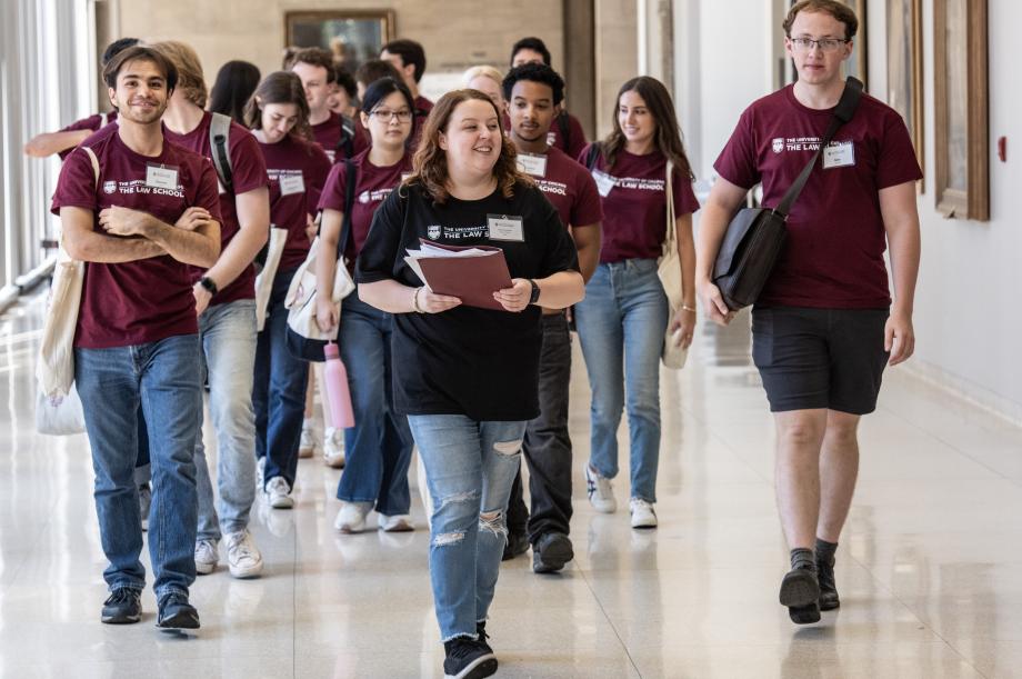 A student leader leads a group of students down a hallway.