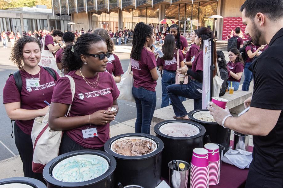Students standing in front of a row of ice cream buckets choosing a flavor to eat.