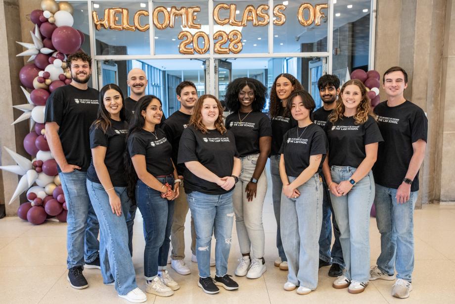 A group of students standing together posing for a photo and all wearing a black t-shirt