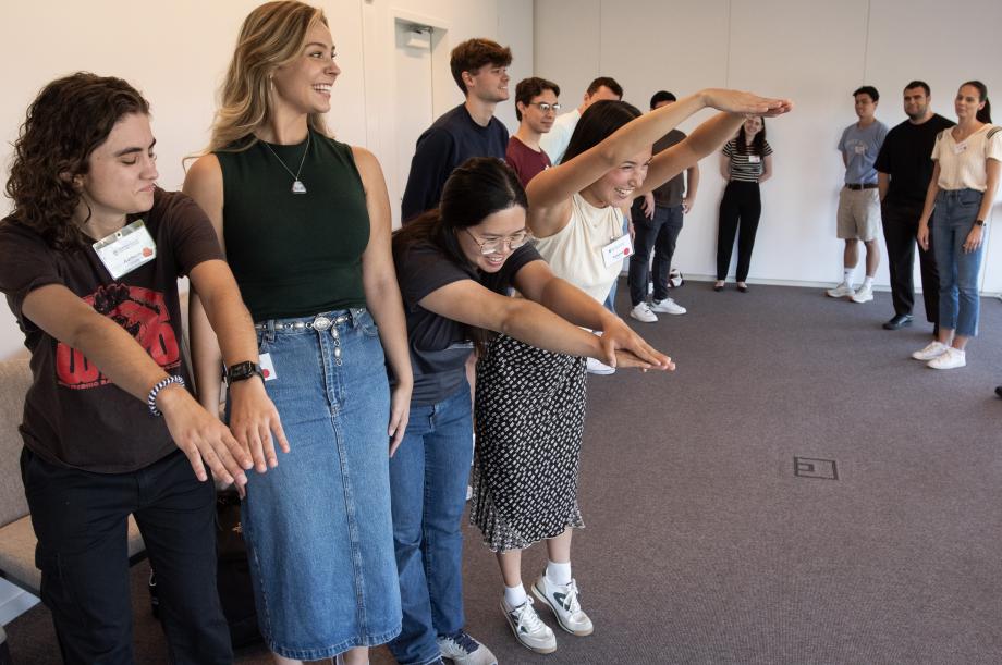 Students standing with their arms raised high performing some sort of activity.