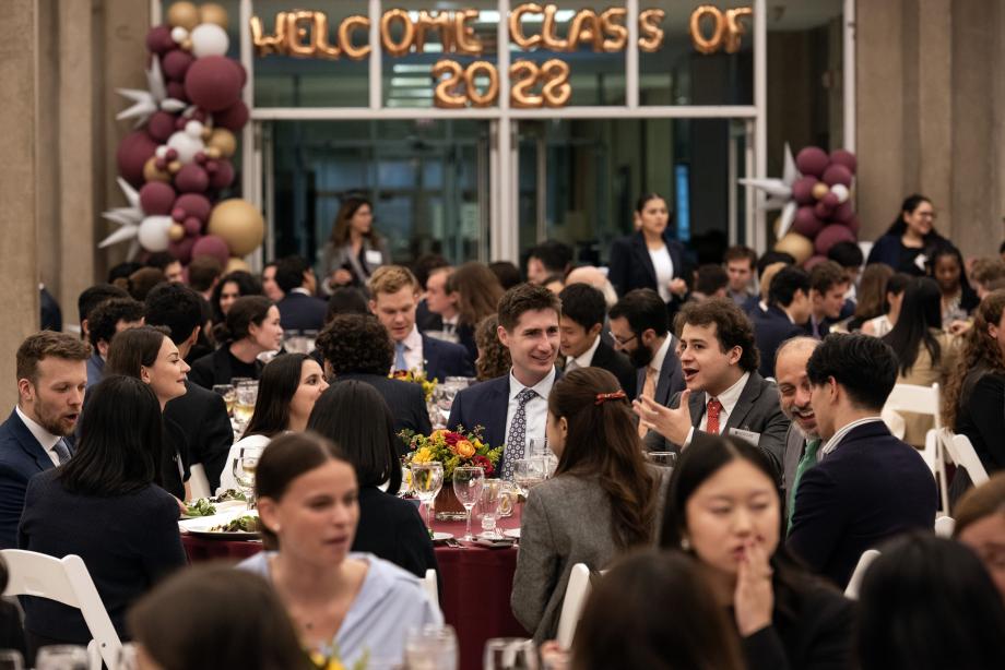 Students sitting at dinner tables with a banner in the background that says Welcome Class of 2028.