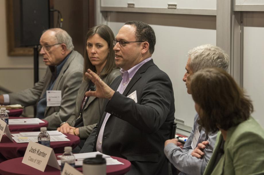 Five alumni sit at tables for a panel