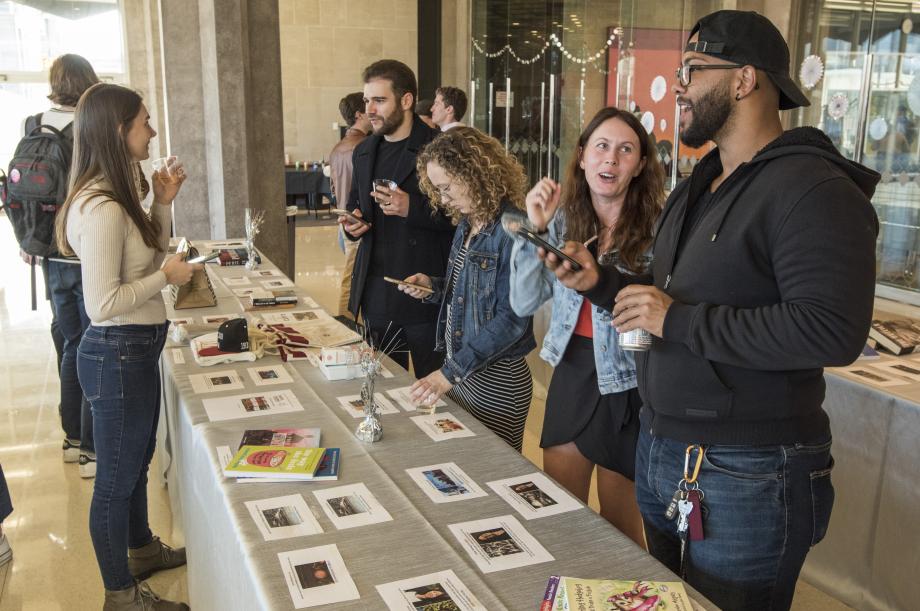 Students line up along a table displaying silent auction items to peruse their options.