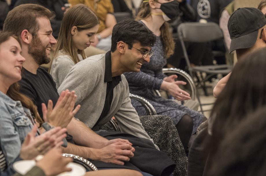 A student in the audience leans forward in laughter.