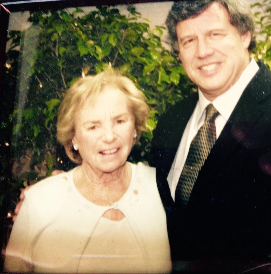 Stone, in suit, and Kennedy, in dress and sweater, smile at the camera.