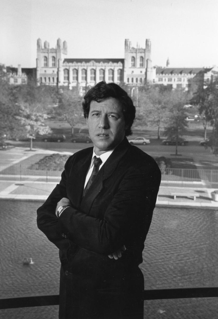 Geoffrey Stone was tapped to serve as University Provost in 1994, during his seventh year as dean of the Law School. Stone in suit stares at the camera with campus buildings behind him.