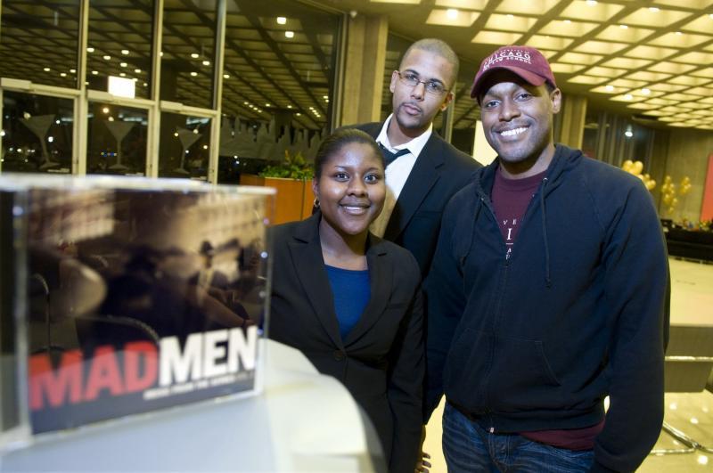 Shareese Pryor, Jason Owens, and Neil Anderson, all '11, show off the soundtrack from Mad Men that played during the silent auction. 