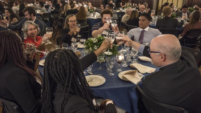 Faculty and students toast each other at their table