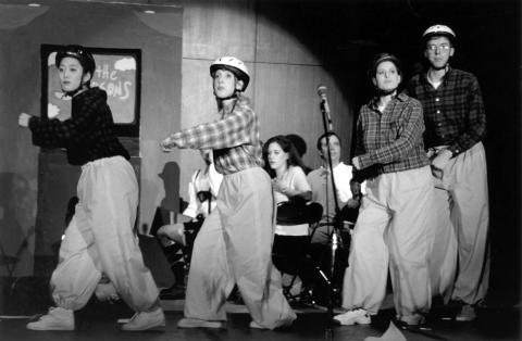 A photo from the Law School Musical of Oompah-Loompahs dressed in yellow rain pants