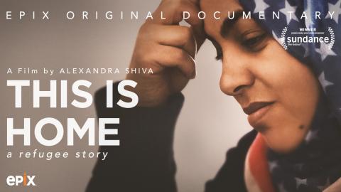 A poster of the documentary 'This Is Home: A Refugee Story.' The poster depicts a woman who is a Syrian refugee. She wears a hijab that bears that pattern of the United States national flag: white stars on a blue background, red and white stripes.