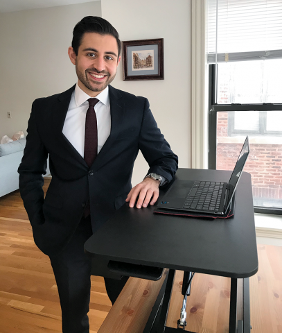 Neema Hakim, '21, stands at his standing desk with his laptop.