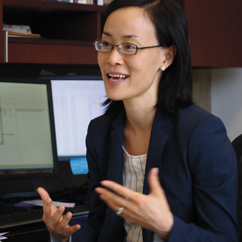 Professor Jennifer Nou sits at her desk.