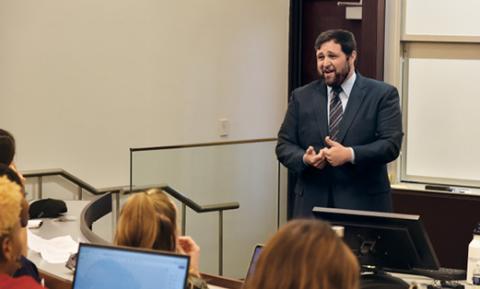 Professor Robert Weinstock speaks at the front of a classroom while students listen.