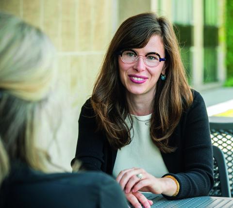 Bridget Fahey sits outside the Law School speaking with a person out of focus