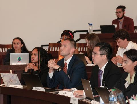 Students sit in a classroom with open laptop as they listen to a lecture