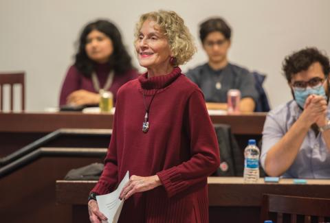 Martha C. Nussbaum wearing a red sweater and holding a piece of paper
