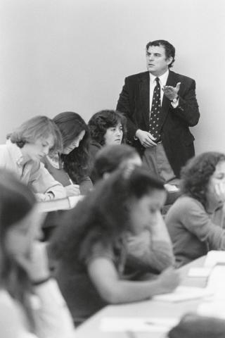 Hutchinson lecturing students, holding his left hand out