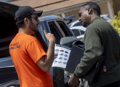 Adriel Ghadoushi speaks with a customer about electric vehicles.