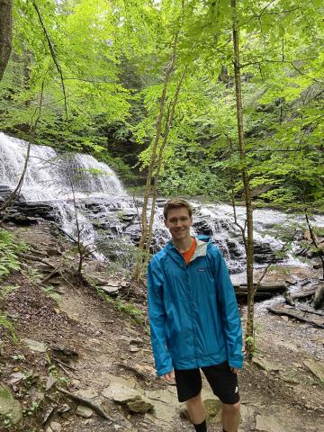 Alec Greven with a waterfall and green foliage behind him.