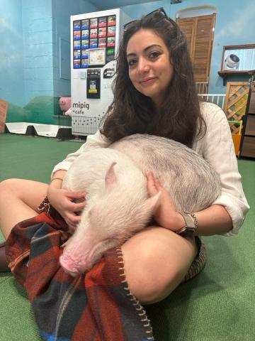 Keyana Banisadre sits on the floor with two piglets on her lap.