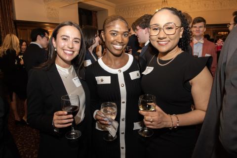 Three students in fancy attire pose for a photograph.