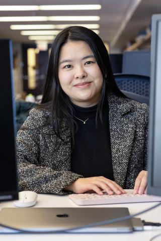 Woman sitting at a computer desk smiling at the camera