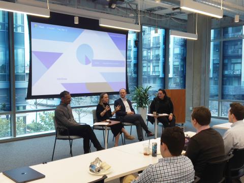 Four people sitting at the front of a room talking to an audience of students