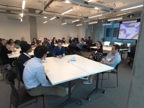 A group of people sitting and talking around a large table.