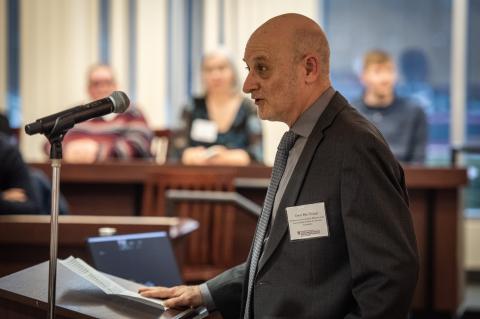 A side view of a man speaking at a lectern.