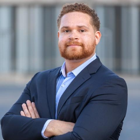 A man standing with his arms crossed looking into the camera.