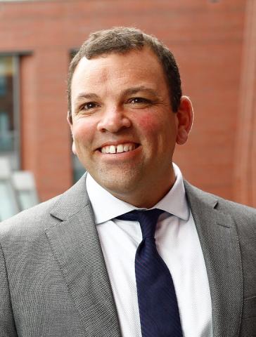 Headshot of a man wearing a grey suit