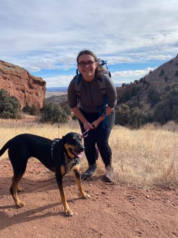 Sarah Beisner poses with a dog with a vista behind them.