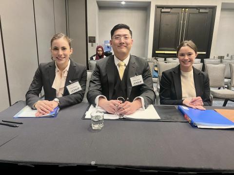 Three students at the regional competition, sitting at counsel's table