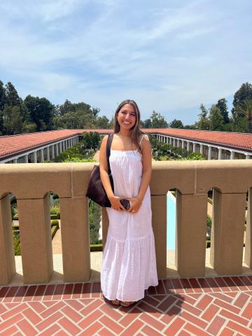 Denita standing on a balcony with a scenic view behind her