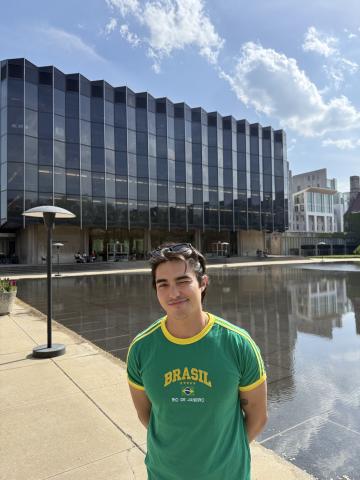 Flavio standing in a green t-shirt with the Law School building behind him