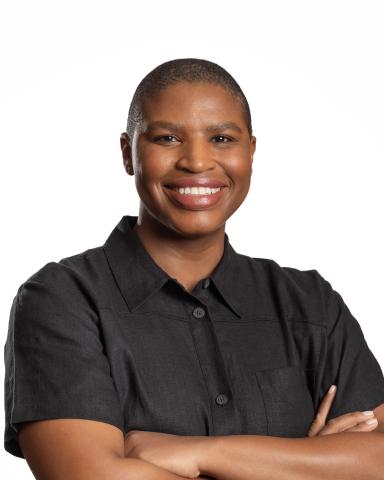 A woman wearing a black polo crosses her arms.