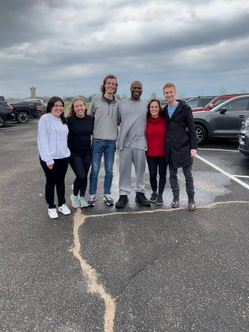 Six people stand in a parking lot for a group photo
