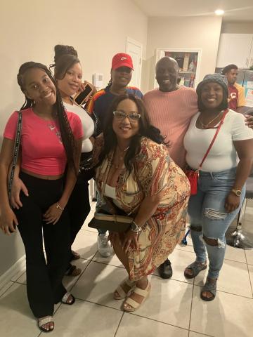 Six people pose for a group photo in a kitchen.