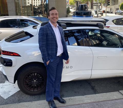 Turner Stanton standing in front of Waymo taxi
