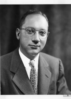 Black and white photograph of Edward Levi with wire-framed glasses and dark suit and tie.