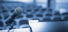 stock image of a microphone at the front of an empty auditorium