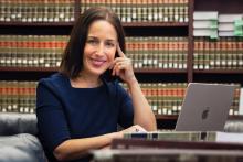 Professor Sarah Konsky sitting in the library with a laptop