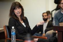 Elizabeth Prelogar, seated in the front of a classrom, gesticulating with her hand as she speaks